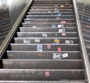 Och rulltrapporna var fulla av klisterlappar för att någon skulle minnas att de stått där de stått. Färdandes längre och längre upp mot någonting kanske nytt... tänkte Anne-Marie Körling som stod där och funderade samma dag i november 2009